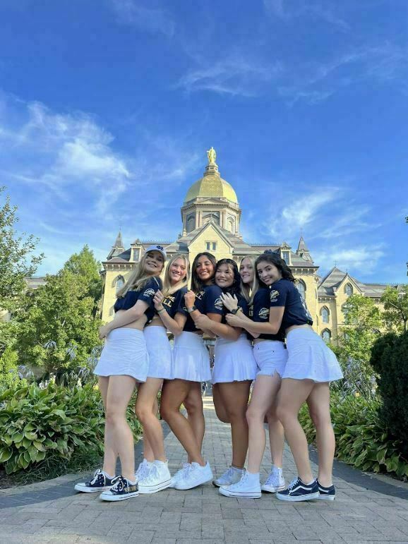 A group of Notre Dame students pose in front of Main Building.