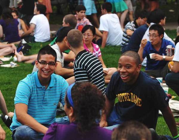 Students sitting in the grass at the opening picnic.
