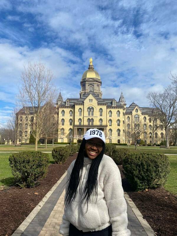 Savannah posing at the dome with her 1972 hat, celebrating over 50 years of women at Notre Dame.