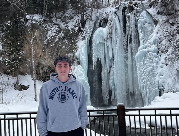 John Blote stands in front of frozen waterfall in the winter.