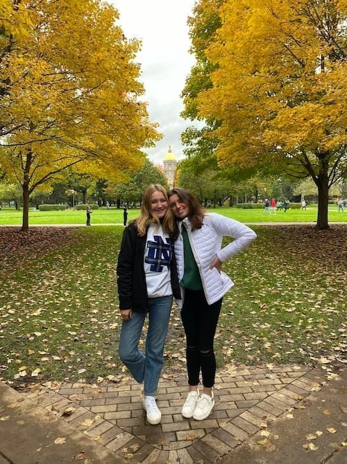 Sara Murray '25 poses with a friend in front of the Notre Dame Main Building during a football home game day.