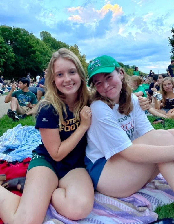 Abbey Donahue sits on the quad at Notre Dame with a friend.