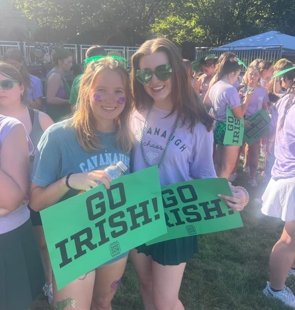 Abbey Donahue '25 holding a Go Irish sign with a friend at a Notre Dame tailgate.