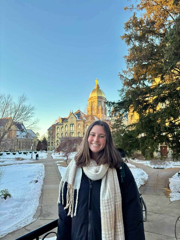 A smiling student in front of the Dome on a winter day with snow.
